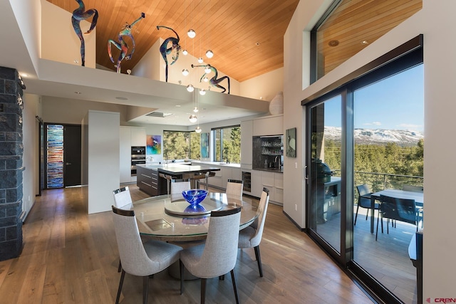 dining space with beverage cooler, high vaulted ceiling, wooden ceiling, and wood finished floors