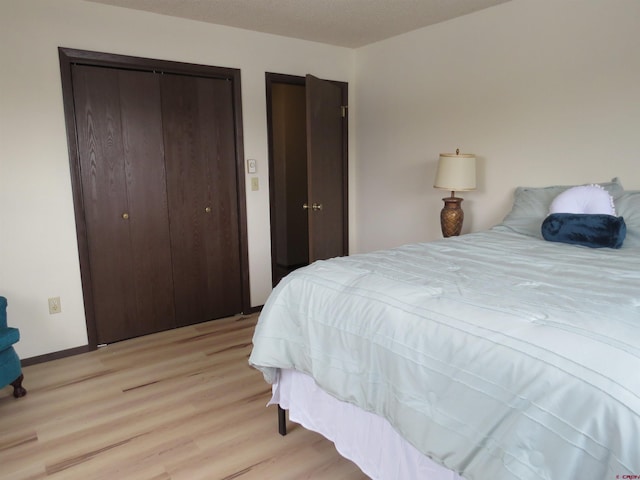 bedroom featuring light wood-type flooring, baseboards, and a closet