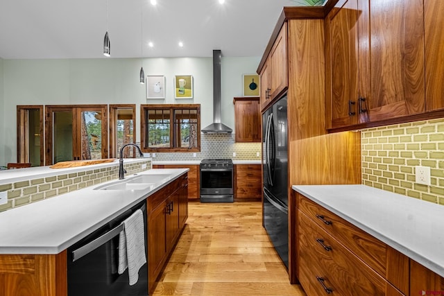 kitchen featuring tasteful backsplash, brown cabinetry, stainless steel appliances, wall chimney range hood, and a sink