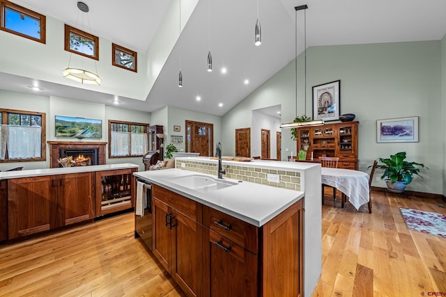 kitchen with light wood-style flooring, a sink, open floor plan, a lit fireplace, and light countertops