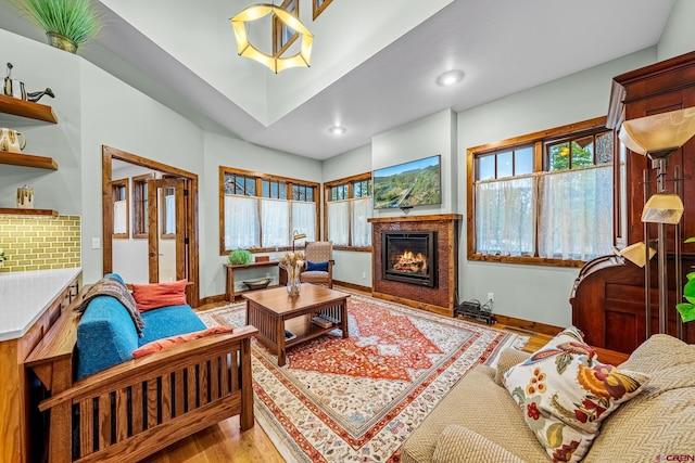 living room with light wood-style floors, a glass covered fireplace, baseboards, and recessed lighting