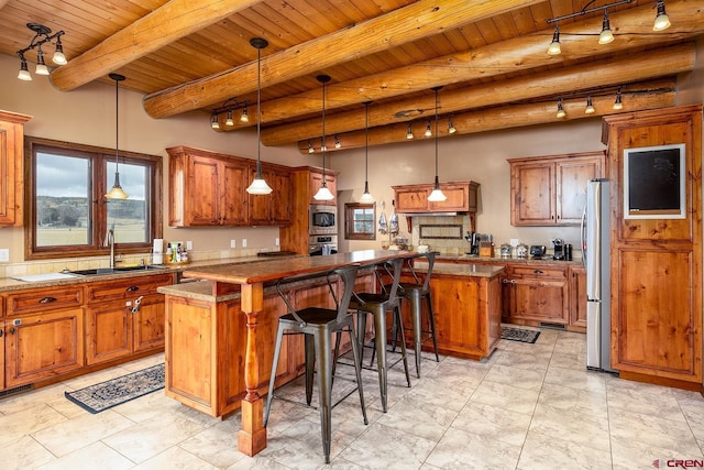 kitchen featuring stainless steel appliances, a center island, brown cabinets, and a sink