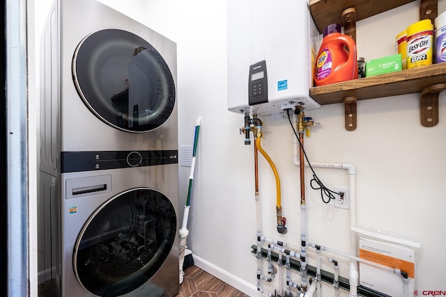 washroom featuring water heater, stacked washer and dryer, laundry area, and baseboards