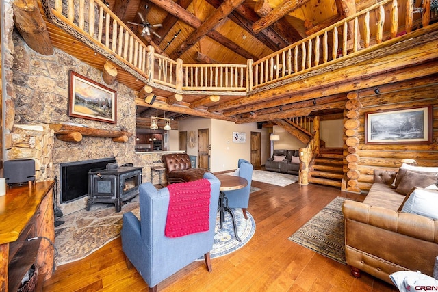 living area featuring wood-type flooring, stairway, a high ceiling, a wood stove, and wooden ceiling