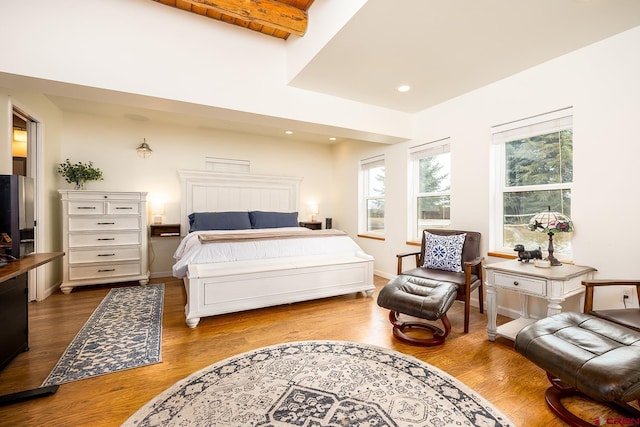 bedroom with baseboards, beamed ceiling, wood finished floors, and recessed lighting