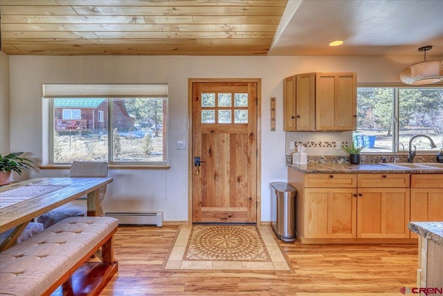 kitchen with decorative backsplash, wood ceiling, baseboard heating, light wood-type flooring, and a sink