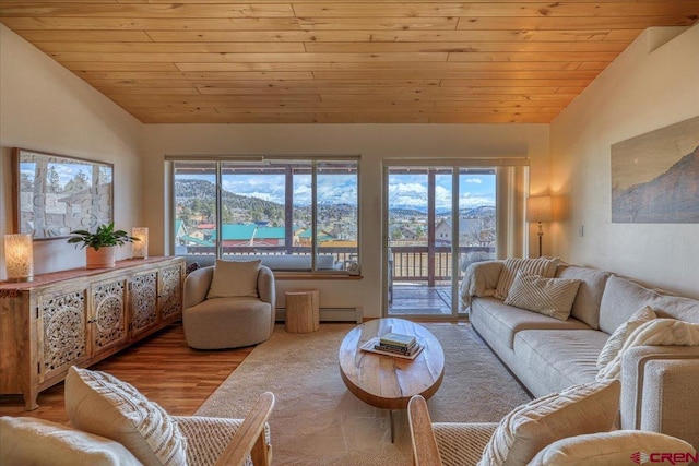 living area with vaulted ceiling, baseboard heating, wood finished floors, and wood ceiling