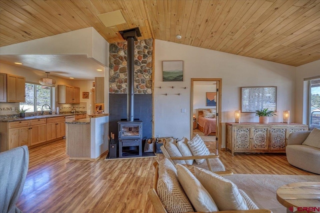 living area featuring a wood stove, light wood finished floors, wood ceiling, and lofted ceiling