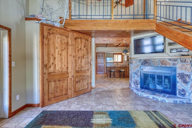 unfurnished living room with stone tile flooring, a high ceiling, a fireplace, and baseboards