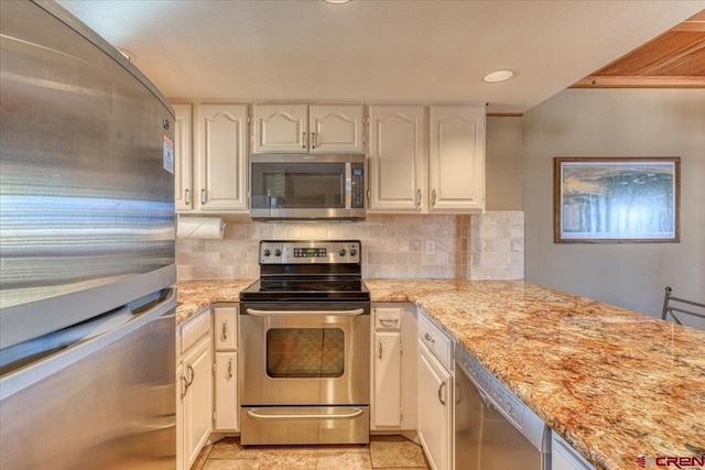 kitchen with tasteful backsplash, recessed lighting, appliances with stainless steel finishes, white cabinetry, and light stone countertops