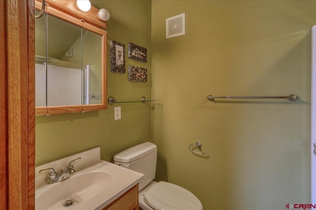 bathroom with toilet, vanity, and visible vents