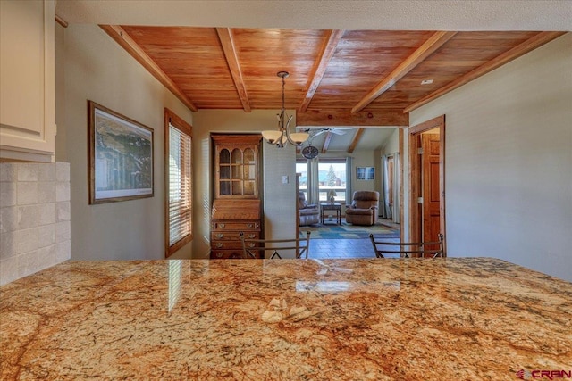 kitchen with wood ceiling, light stone counters, and beamed ceiling