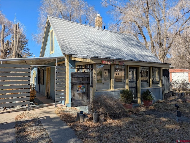 view of front of house featuring metal roof and a chimney