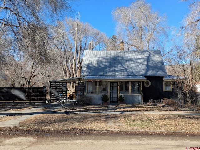 view of front of home featuring a chimney, metal roof, fence, an attached carport, and driveway