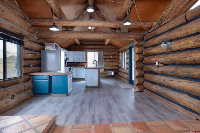 kitchen featuring lofted ceiling with beams, dark wood-style flooring, refrigerator, blue cabinets, and pendant lighting