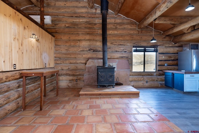 unfurnished living room with a wood stove, vaulted ceiling with beams, and wood finished floors