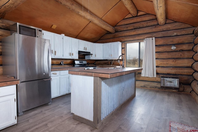 kitchen featuring appliances with stainless steel finishes, wood finished floors, vaulted ceiling with beams, under cabinet range hood, and a sink