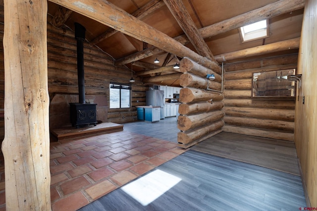 interior space featuring a wood stove, rustic walls, lofted ceiling with beams, and wood finished floors