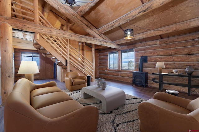 living area featuring vaulted ceiling with beams, a wood stove, stairway, and a wealth of natural light