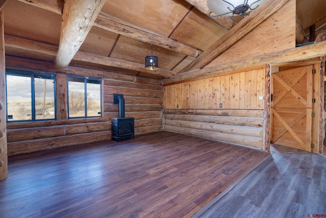 spare room with lofted ceiling with beams, wood ceiling, log walls, dark wood finished floors, and a wood stove