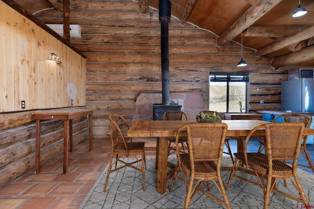 dining area with a wood stove and vaulted ceiling with beams