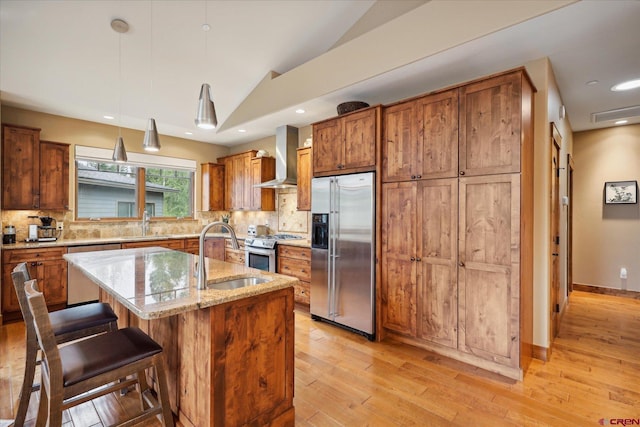 kitchen with tasteful backsplash, wall chimney exhaust hood, appliances with stainless steel finishes, vaulted ceiling, and a sink