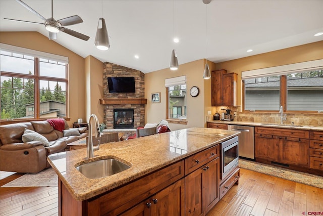 kitchen featuring stainless steel appliances, open floor plan, a fireplace, and a sink