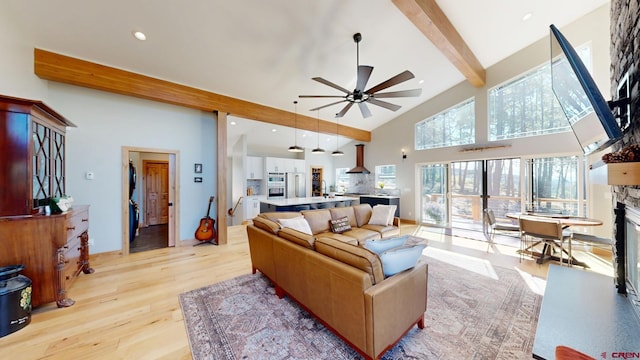 living area featuring high vaulted ceiling, recessed lighting, a fireplace, light wood-type flooring, and beam ceiling