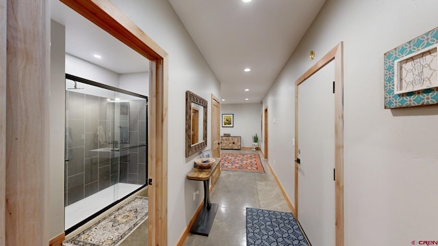 corridor with concrete floors, baseboards, and recessed lighting