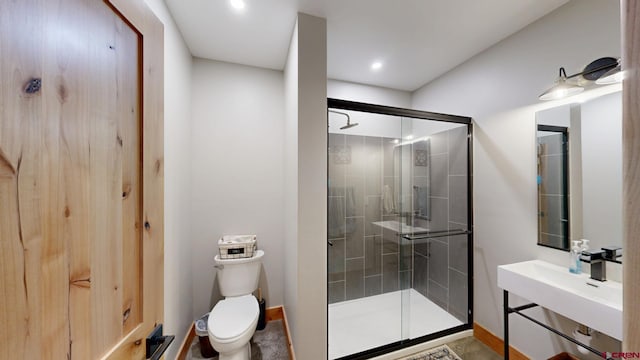 bathroom with toilet, a shower stall, and a sink