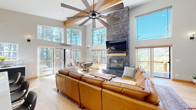 living area with light wood-type flooring, a fireplace, beam ceiling, and baseboards