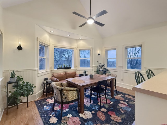 dining space featuring lofted ceiling, ceiling fan, wood finished floors, and wainscoting