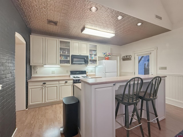 kitchen featuring an ornate ceiling, light countertops, visible vents, light wood-type flooring, and white appliances