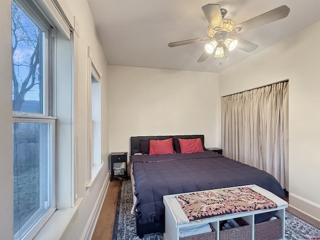 bedroom with ceiling fan, wood finished floors, and baseboards