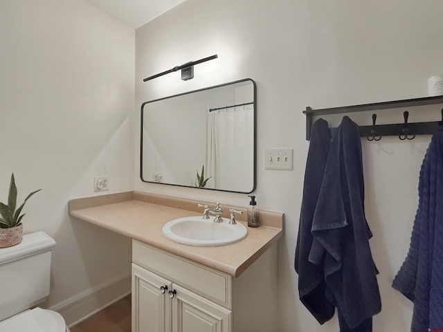 bathroom featuring toilet, baseboards, and vanity