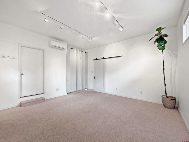 empty room with an AC wall unit, light carpet, baseboards, and a barn door