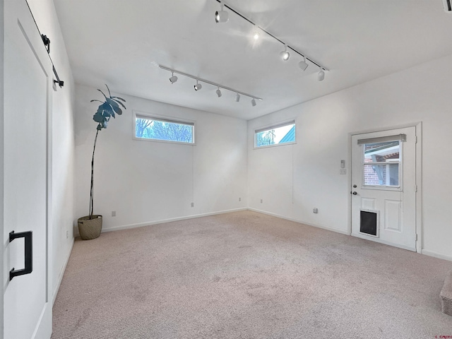 carpeted empty room with a wealth of natural light and baseboards