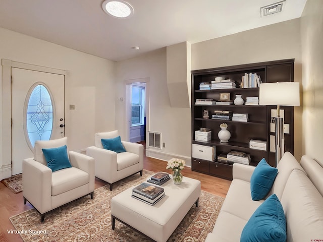 living area with visible vents, baseboards, and wood finished floors