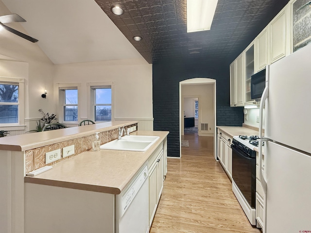 kitchen with light wood-type flooring, white appliances, light countertops, and a sink