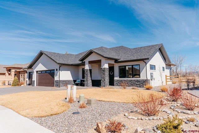 view of front of house featuring driveway, stone siding, roof with shingles, an attached garage, and stucco siding