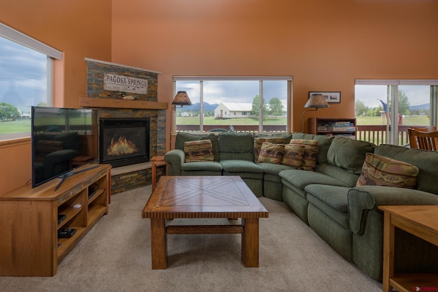 carpeted living room with a fireplace, a high ceiling, and a wealth of natural light