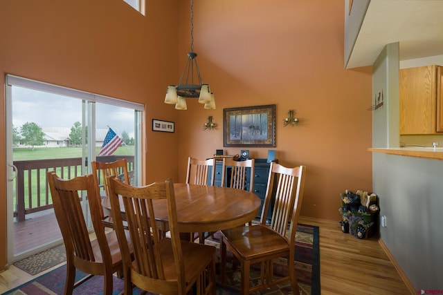 dining area with light wood-style floors, a high ceiling, and baseboards