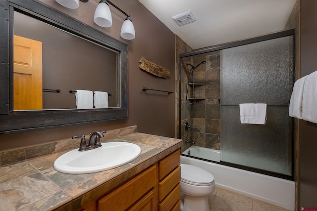 bathroom featuring bath / shower combo with glass door, visible vents, toilet, vanity, and tile patterned flooring