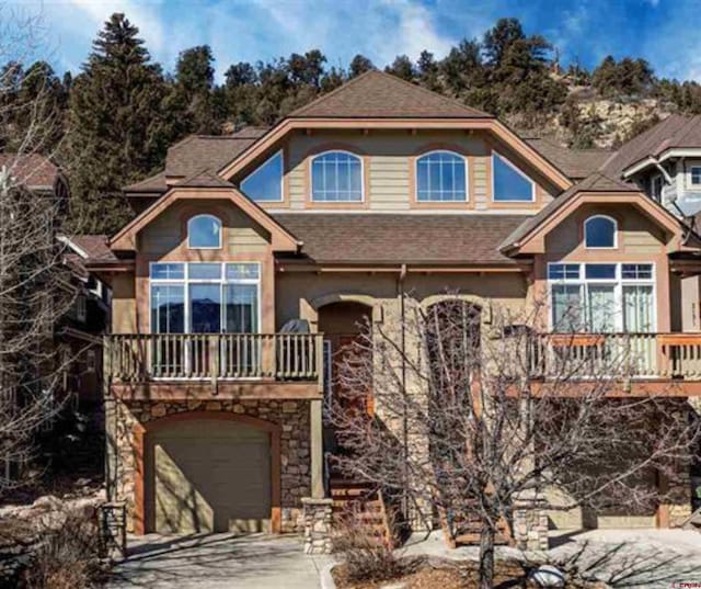 view of front of home featuring a shingled roof, stone siding, an attached garage, and concrete driveway