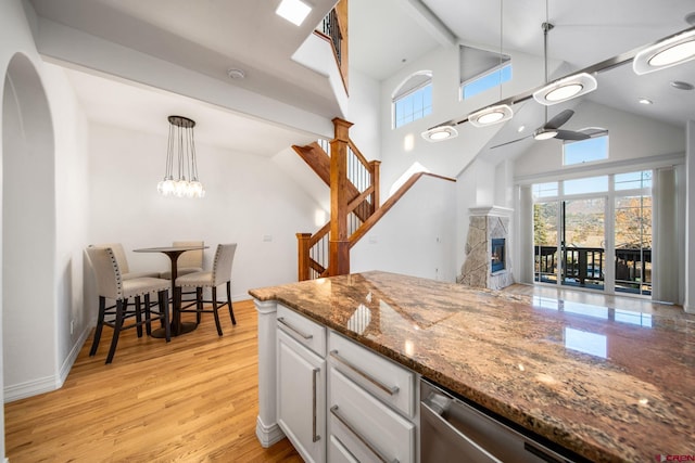 kitchen with a glass covered fireplace, a healthy amount of sunlight, light wood finished floors, and ceiling fan with notable chandelier