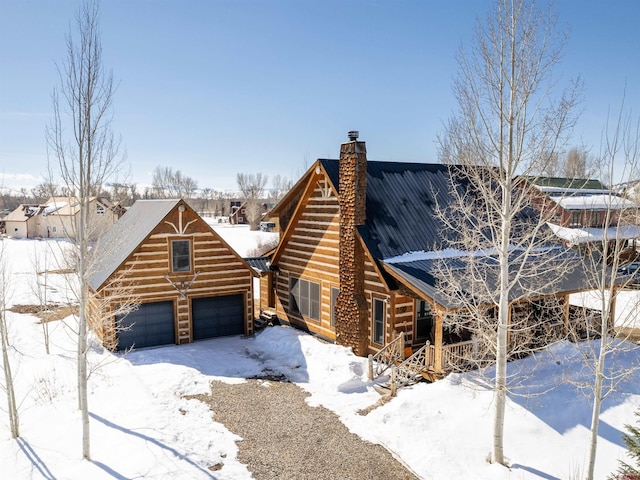 view of front of home with metal roof, log exterior, and a chimney