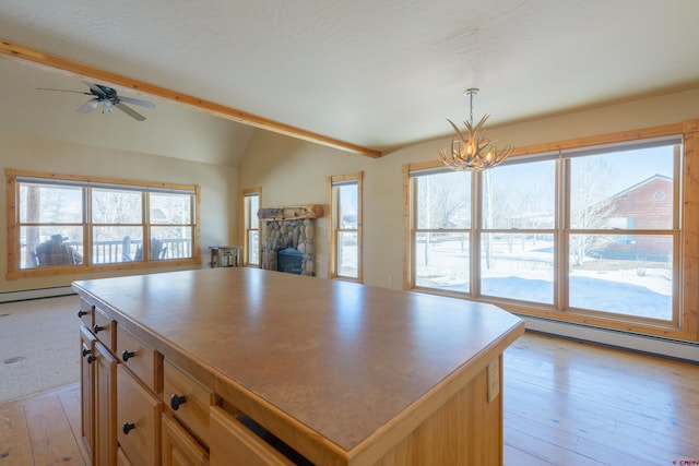 kitchen with vaulted ceiling, a stone fireplace, open floor plan, and a wealth of natural light