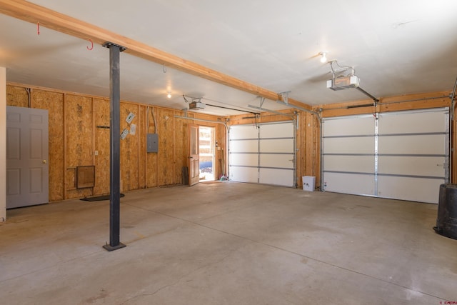 garage with wood walls, electric panel, and a garage door opener