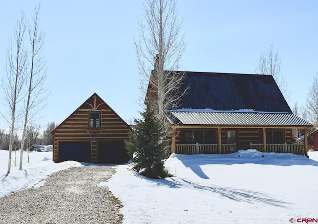 log cabin featuring metal roof, covered porch, a garage, an outdoor structure, and a barn