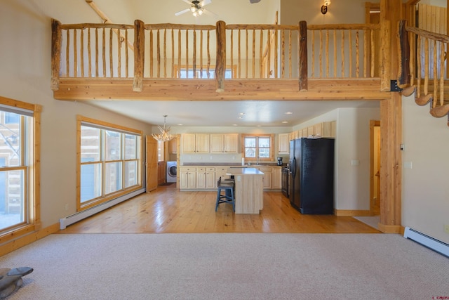 kitchen featuring light colored carpet, a baseboard heating unit, washer / clothes dryer, and freestanding refrigerator